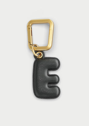 Charm Untags per iPhone a forma di lettera E, effetto pelle in colore nero, con moschettone per attaccare l’accessorio alla cover