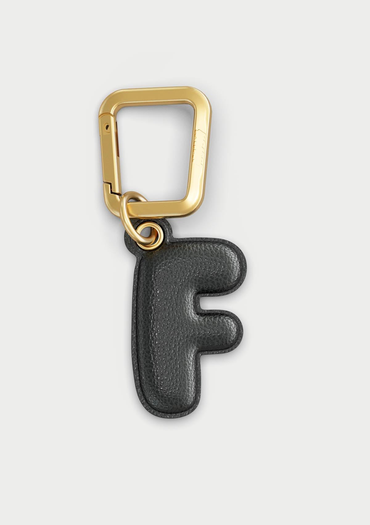 Charm Untags per iPhone a forma di lettera F, effetto pelle in colore nero, con moschettone per attaccare l’accessorio alla cover