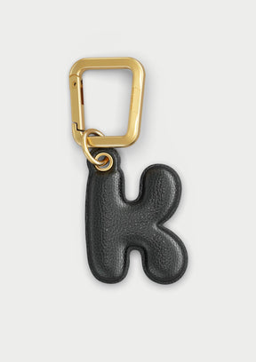 Charm Untags per iPhone a forma di lettera K, effetto pelle in colore nero, con moschettone per attaccare l’accessorio alla cover