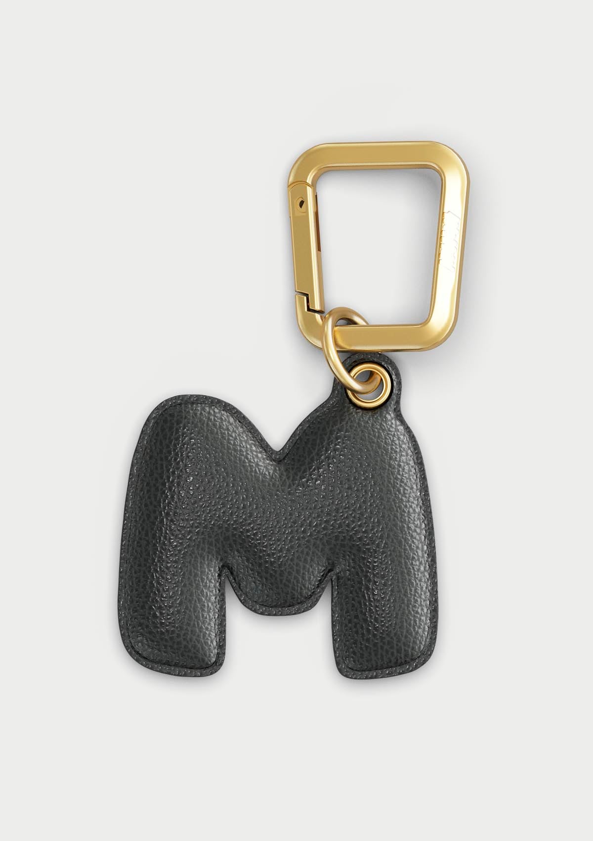 Charm Untags per iPhone a forma di lettera M, effetto pelle in colore nero, con moschettone per attaccare l’accessorio alla cover