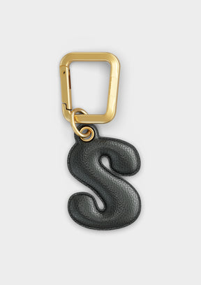 Charm Untags per iPhone a forma di lettera S, effetto pelle in colore nero, con moschettone per attaccare l’accessorio alla cover